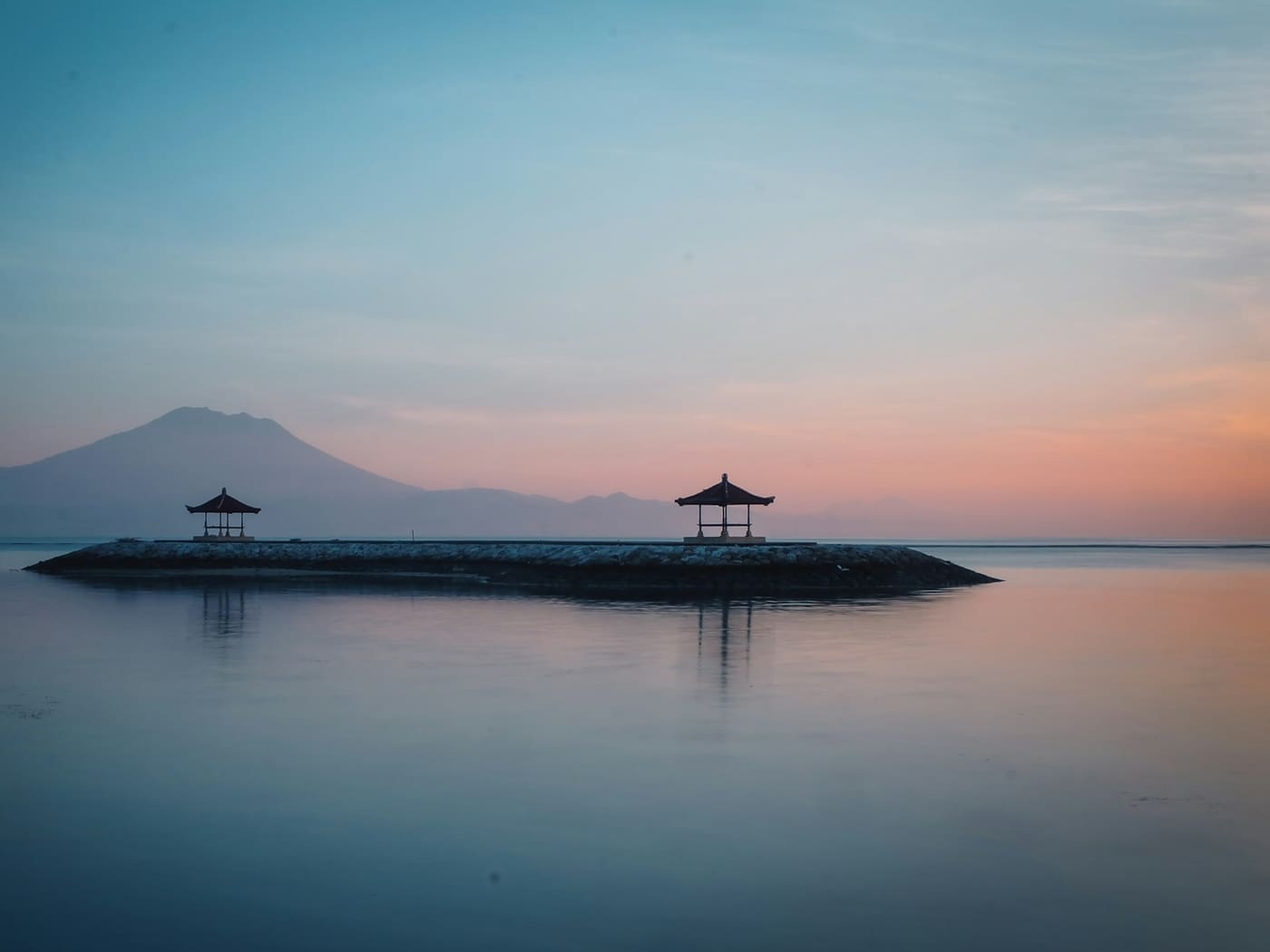 Sunrise over the sea at Sanur, with traditional pavilions on the breakwater